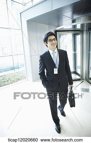 A business man with an access card and a briefcase entering an office building View Large Photo Image Stock Image - A business man with an access card and a briefcase entering an office building. Fotosearch