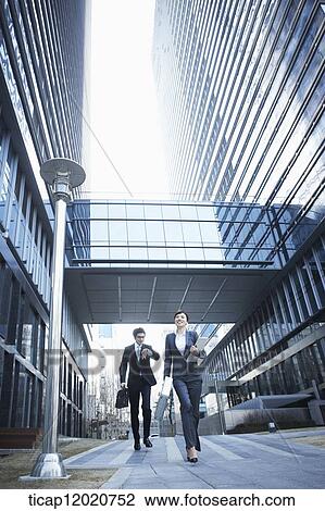 A business woman and a business man running between office buildings View Large Photo Image Stock Image - A business woman and a business man running between office buildings . Fotosearch