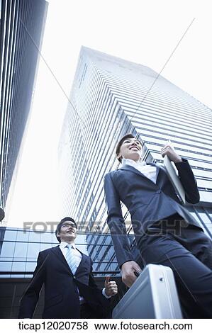 A business woman and a business man with briefcases running between office buildings View Large Photo Image Stock Photo - A business woman and a business man with briefcases running between office buildings. Fotosearch
