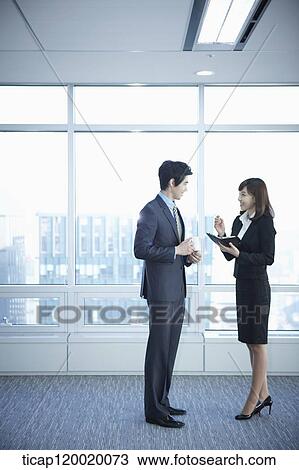 A business woman and a man standing in a building discussing schedule View Large Photo Image Stock Image - A business woman and a man standing in a building discussing schedule. Fotosearch