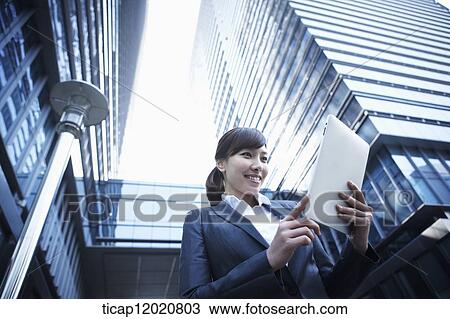 A business woman using a tablet device between office buildings View Large Photo Image Stock Image - A business woman using a tablet device between office buildings. Fotosearch