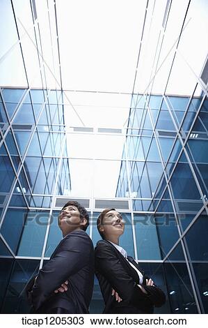 Stock Image - A businessman and woman standing with their backs together. Fotosearch