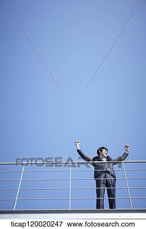 A businessman putting his hands up in the sky View Large Photo Image Stock Photo - A businessman putting his hands up in the sky. Fotosearch