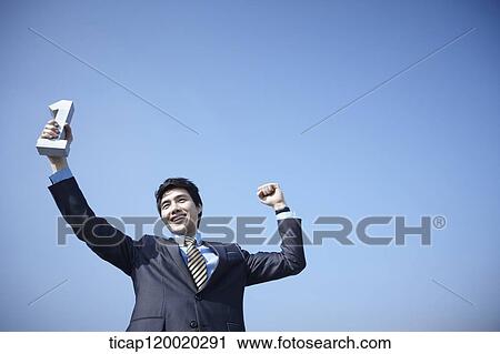 A businessman raising a block with no. 1 shape up high in the sky View Large Photo Image Stock Image - A businessman raising a block with no. 1 shape up high in the sky. Fotosearch