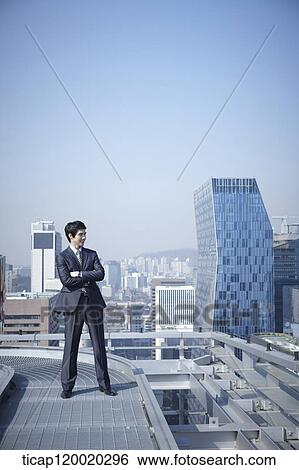 A businessman standing on a rooftop View Large Photo Image Stock Photograph - A businessman standing on a rooftop. Fotosearch