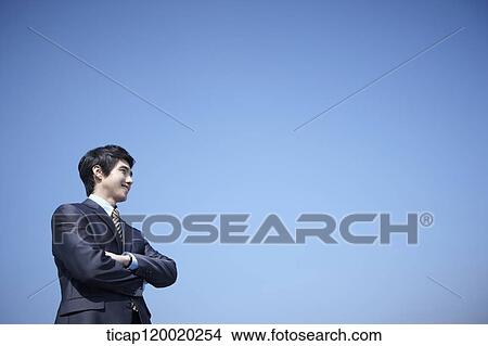 Picture - A businessman standing with arms crossed. Fotosearch