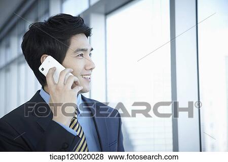 A businessman talking on a mobile phone View Large Photo Image Stock Photo - A businessman talking on a mobile phone. Fotosearch