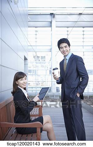 A businesswoman and man, each holding a touch pad and a coffee View Large Photo Image Stock Image - A businesswoman and man, each holding a touch pad and a coffee. Fotosearch