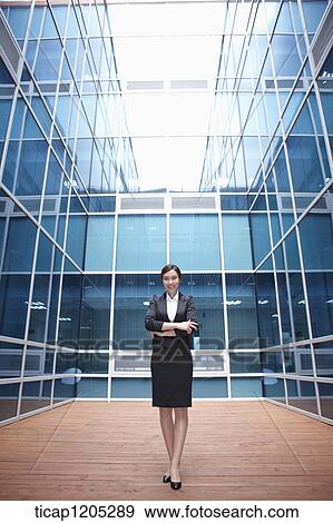 A businesswoman standing in a modern building with her arms crossed View Large Photo Image Stock Photo - A businesswoman standing in a modern building with her arms crossed. Fotosearch
