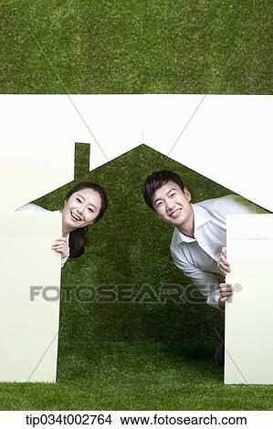 Picture - a couple hiding in the paper house. Fotosearch