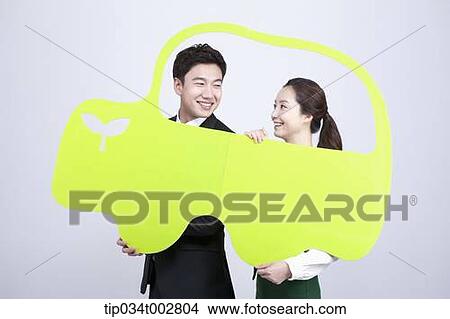 Picture - a couple holding a green paper car . Fotosearch