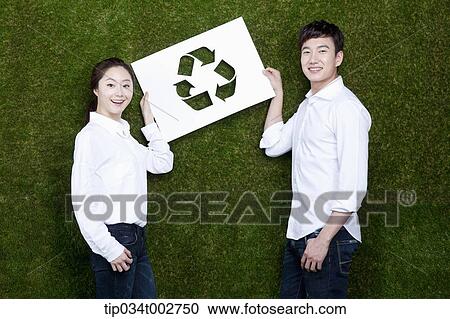 a couple holding a paper cut of recycling sign View Large Photo Image Stock Image - a couple holding a paper cut of recycling sign. Fotosearch