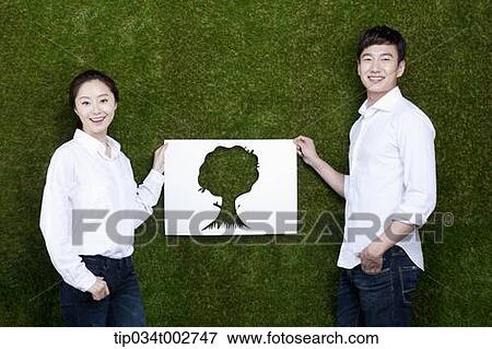Stock Photo - a couple holding a paper cut of tree. Fotosearch