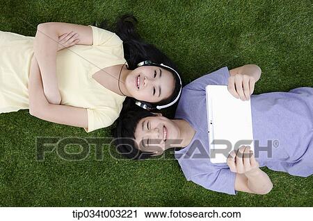 a couple lying on the ground with headphone and tablet PC View Large Photo Image Stock Image - a couple lying on the ground with headphone and tablet PC. Fotosearch