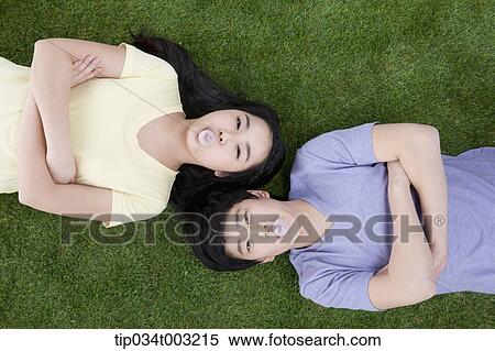 a couple lying on the ground with their arms folded View Large Photo Image Stock Photography - a couple lying on the ground with their arms folded . Fotosearch