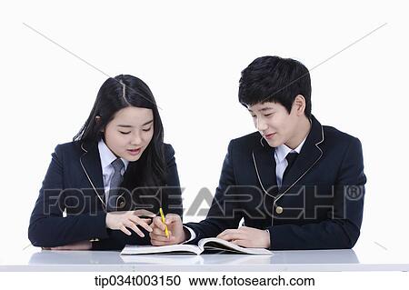 Stock Image - a couple of students studying a book together. Fotosearch
