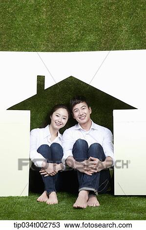 Stock Image - a couple sitting together in the paper house. Fotosearch