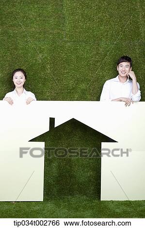 Stock Photograph - a couple standing behind the paper house. Fotosearch