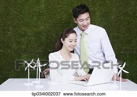 Stock Photo - a couple using computer next to the pinwheels on the table . Fotosearch