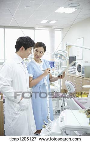 Stock Photo - A dentist and a nurse discussing about a report together. Fotosearch