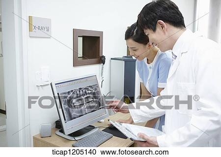 A dentist and a nurse looking at a teeth x-ray in a computer View Large Photo Image Stock Image - A dentist and a nurse looking at a teeth x-ray in a computer. Fotosearch