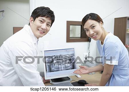 A dentist and a nurse standing with a computer between View Large Photo Image Stock Photograph - A dentist and a nurse standing with a computer between. Fotosearch