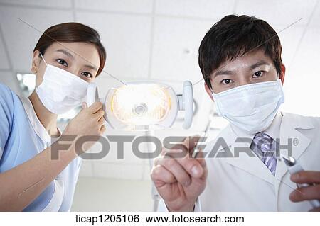 A dentist holding dental tools while a nurse managing dental light View Large Photo Image Stock Photograph - A dentist holding dental tools while a nurse managing dental light. Fotosearch