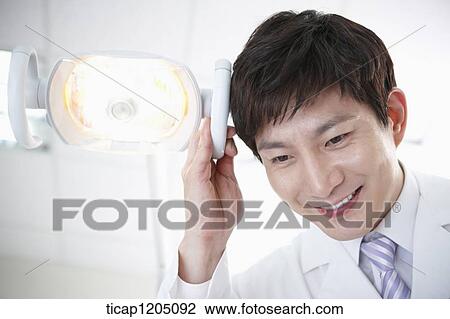 A dentist next to a dental light View Large Photo Image Stock Image - A dentist next to a dental light. Fotosearch