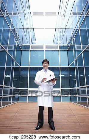 Stock Photo - A doctor holding a report standing in middle of a modern building. Fotosearch