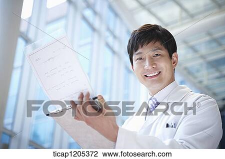 Stock Image - A doctor in a white dressing gown smiling at a report in his hands. Fotosearch