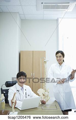 A female surgeon standing next to a male surgeon's office desk View Large Photo Image Stock Photograph - A female surgeon standing next to a male surgeon's office desk. Fotosearch