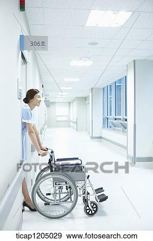 A nurse exiting a room with an empty wheelchair View Large Photo Image Stock Photo - A nurse exiting a room with an empty wheelchair. Fotosearch