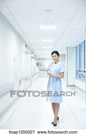A nurse holding a report in an empty hospital corridor View Large Photo Image Stock Photo - A nurse holding a report in an empty hospital corridor. Fotosearch