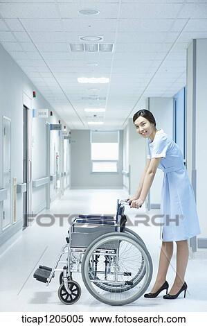 A nurse holding a wheelchair in hospital corridor View Large Photo Image Stock Photography - A nurse holding a wheelchair in hospital corridor. Fotosearch