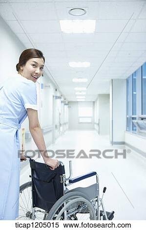 A nurse looking back while walking away with an empty wheelchair in hospital corridor View Large Photo Image Stock Photography - A nurse looking back while walking away with an empty wheelchair in hospital corridor . Fotosearch