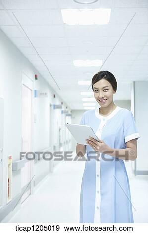 A nurse smiling while holding a report in an empty corridor View Large Photo Image Stock Photo - A nurse smiling while holding a report in an empty corridor. Fotosearch