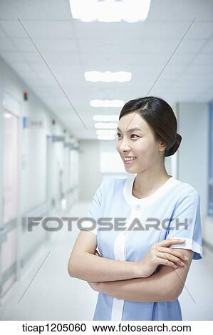 A nurse standing side ways in an empty hospital corridor with her arms crossed View Large Photo Image Stock Image - A nurse standing side ways in an empty hospital corridor with her arms crossed. Fotosearch