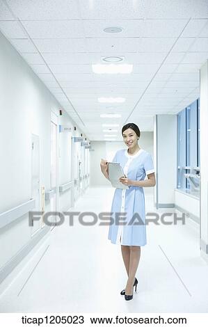 A nurse standing with a report in an empty corridor View Large Photo Image Stock Image - A nurse standing with a report in an empty corridor. Fotosearch