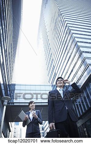A smiling business man and a business woman walking between office buildings View Large Photo Image Stock Image - A smiling business man and a business woman walking between office buildings. Fotosearch