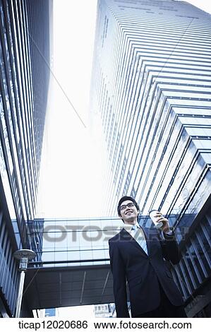 A smiling business man walking with a coffee cup in his hand View Large Photo Image Stock Photograph - A smiling business man walking with a coffee cup in his hand. Fotosearch