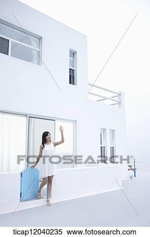 A woman coming out of a white house waving her hand View Large Photo Image Stock Photography - A woman coming out of a white house waving her hand. Fotosearch