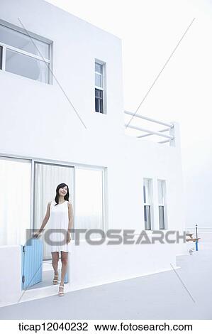 Stock Image - A woman getting out of white house. Fotosearch