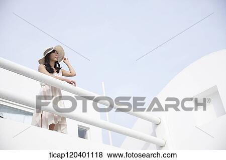 A woman holding her straw hat and wearing a white dress leaning her hands on a white fence View Large Photo Image Stock Photo - A woman holding her straw hat and wearing a white dress leaning her hands on a white fence. Fotosearch