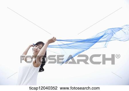 Stock Image - A woman holding up a thin transparent blue linen. Fotosearch