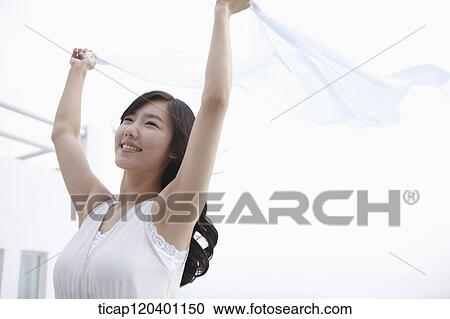 A woman in a white dress next to a white building is holding a white sheet in the air View Large Photo Image Stock Image - A woman in a white dress next to a white building is holding a white sheet in the air. Fotosearch