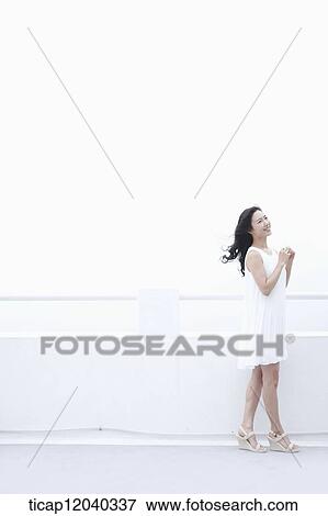 A woman in a white dress next to a white fence with wind in her hair View Large Photo Image Stock Photo - A woman in a white dress next to a white fence with wind in her hair. Fotosearch