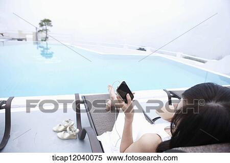 A woman in white dress listening to music lying on a sunbed View Large Photo Image Stock Photography - A woman in white dress listening to music lying on a sunbed . Fotosearch