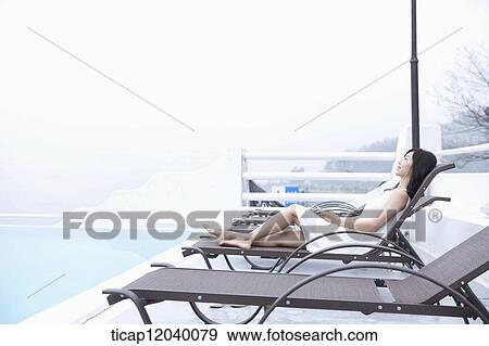 A woman in white dress lying on a sunbed next to a pool View Large Photo Image Stock Photo - A woman in white dress lying on a sunbed next to a pool. Fotosearch