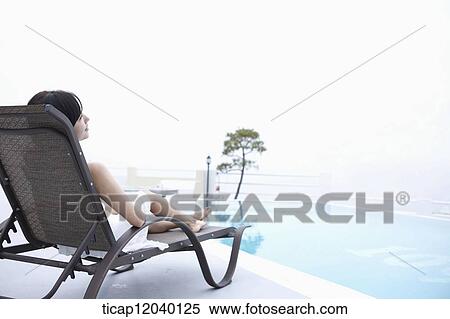 A woman in white dress lying on a sunbed facing back View Large Photo Image Stock Photography - A woman in white dress lying on a sunbed facing back. Fotosearch