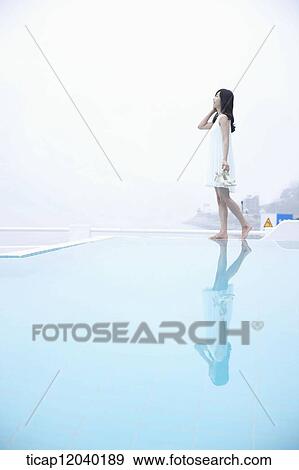A woman in white dress posing on the edge of a pool View Large Photo Image Stock Photo - A woman in white dress posing on the edge of a pool. Fotosearch